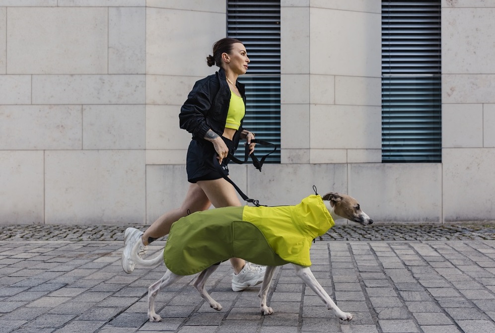 Una donna corre con il suo cane vestito con una mantella dell'azienda Cloud7: il brand è presente all'inaugurazione del nuovo Pet Design District a Milano